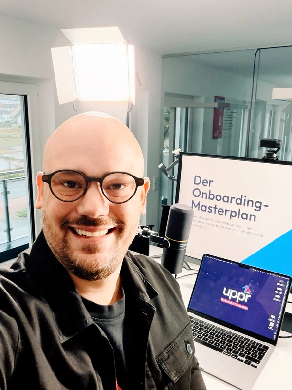 Marcel Schöne vor einem Webinar zum Onboarding-Masterplan, mit Mikrofon und Laptop
