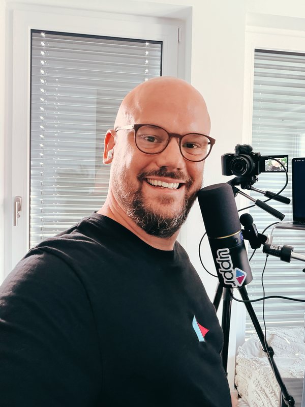 Marcel Schöne am Podcast-Mikrofon mit uppr-Logo, daneben die Kamera